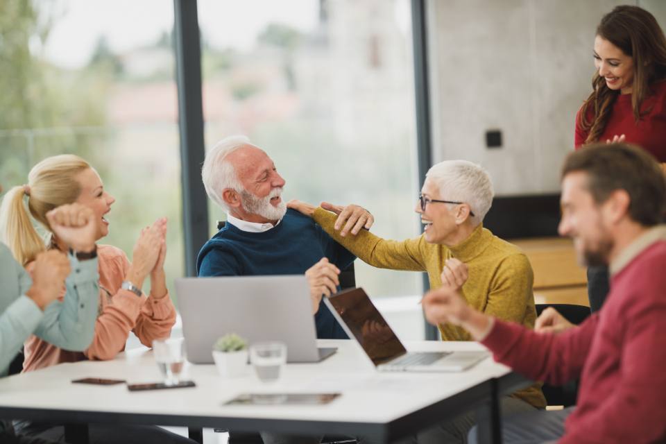 Colleagues around a meeting table applauding