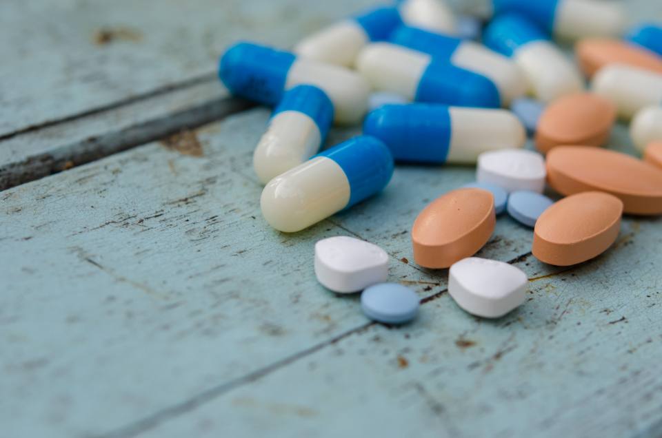 Tablets and capsules scattered on a blue wooden table